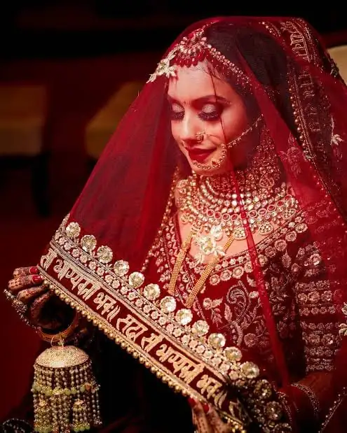 Indian bride in a red embroidered veil and gold jewellery