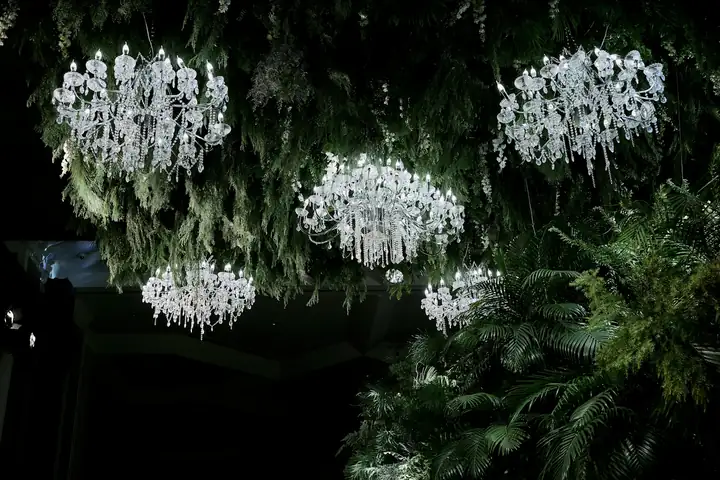 Chandeliers hanging among greenery — @quince.event on Instagram