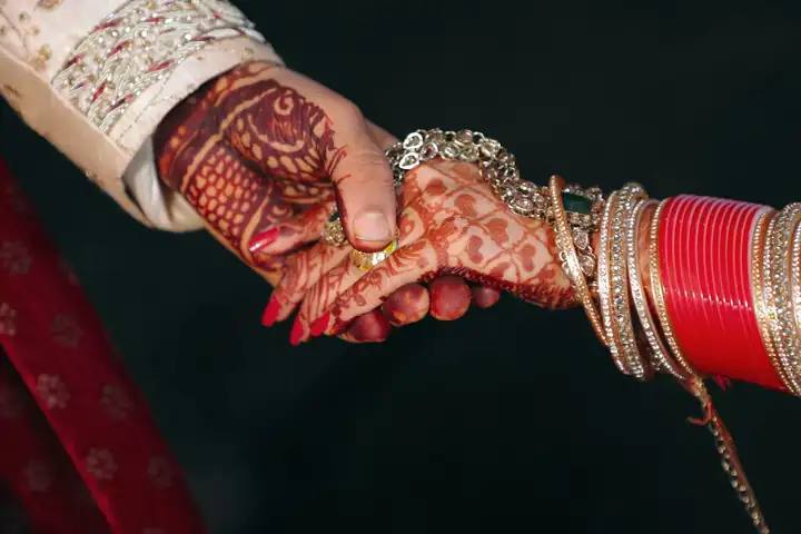 Bride and groom holding hands with mehendi